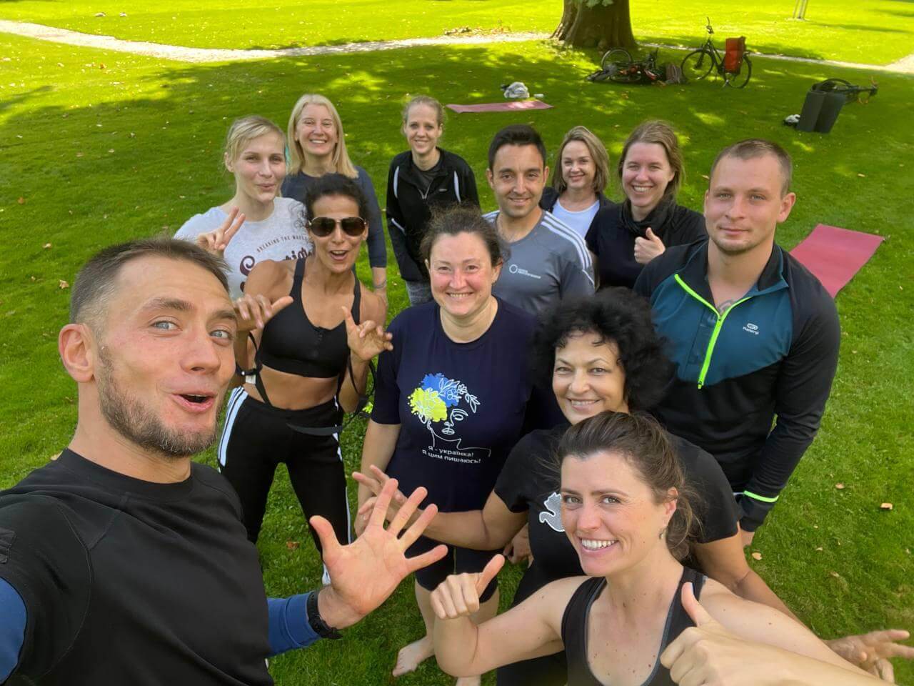 Trainer und Teilnehmende bei einem Yoga- und Fitnesskurs im Stuttgarter Park – Gemeinschaft, Integration und Freude durch Bewegung.