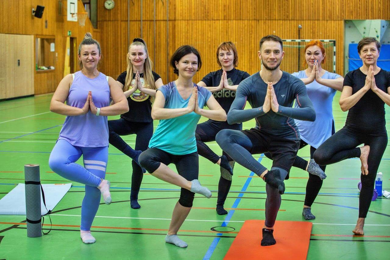 Yoga-Kurs für Geflüchtete in Stuttgart – Trainer Vitalii Opryshchenko leitet Teilnehmerinnen in einer Yoga Position an.